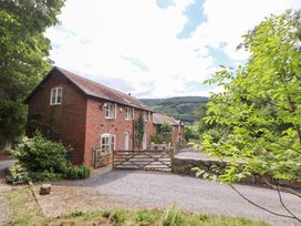 A house with a gate and driveway surrounded by trees at Bryn Howell Stables Trevor near Llangollen