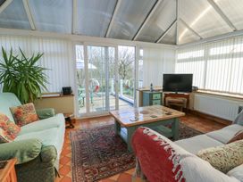 A conservatory with sofas and a table at Crow's Nest Cottage Tynygongl near Benllech