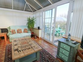 A conservatory with a sofa and coffee table at Crow's Nest Cottage Tynygongl near Benllech