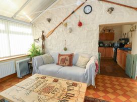 A conservatory with a sofa and a coffee table at Crow's Nest Cottage in Tynygongl near Benllech