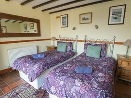 A bedroom with twin beds and a bedside table at Crow's Nest Cottage Tynygongl near Benllech