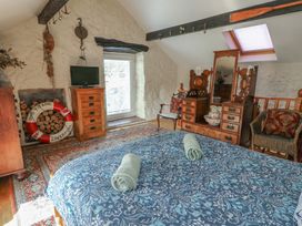 A bedroom with a bed and wooden furniture at Crow's Nest Cottage in Tynygongl near Benllech