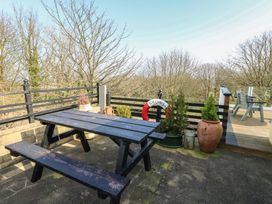 An outdoor area with a table and benches at Crow's Nest Cottage in Tynygongl near Benllech