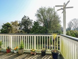 A balcony with potted plants and a directional sign at Crow's Nest Cottage Tynygongl near Benllech