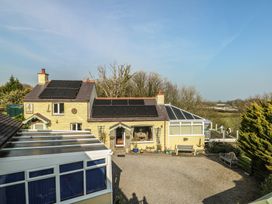 A house with solar panels and a patio area at Crow's Nest Cottage Tynygongl near Benllech