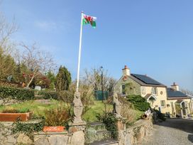 An outdoor view of a house with a flag and parking sign at Crow's Nest Cottage near Tynygongl, Benllech