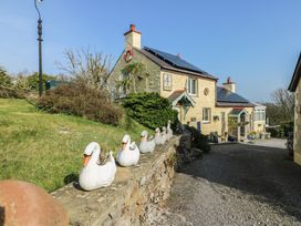 An outdoor photo of a house with a garden and decorative swans at Crow's Nest Cottage Tynygongl near Benllech
