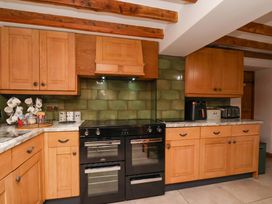 A kitchen with wooden cabinets and a black stove at Boundcliffe Farm in Allerston near Pickering