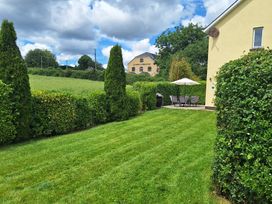 A garden with grass, seating area, and barbecue at 19 River Glen, Curracloe, County Wexford