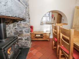 A dining area with a fireplace and wooden furniture at Tyddyn Goronwy in Talybont