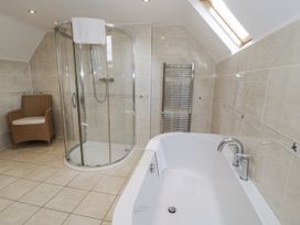 A bathroom featuring a shower, a bathtub, and a chair at Tyddyn Goronwy in Talybont