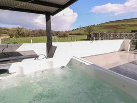 A hot tub and table with view of hills and grass at Meadow View in Laugharne