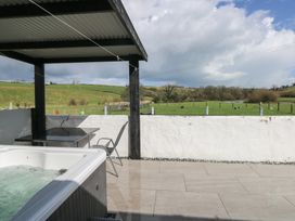 An outdoor area with a hot tub and seating at Meadow View in Laugharne