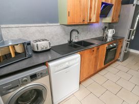 A kitchen with appliances including a washing machine and dishwasher at Dylan's Court in Laugharne