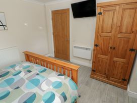 A bedroom with a bed, wardrobe, and television at Dylan's Court in Laugharne