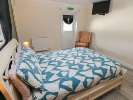 A bedroom with a bed, chair and television at Dylan's Court in Laugharne