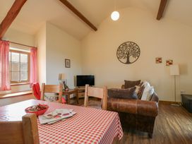 A living room with a table, sofa, and television at Poppy Cottage in Caeathro near Caernarfon