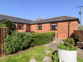 A brick bungalow with three windows a door and hedges in the front garden at 2 Pines Farm Cottages in Ulleskelf