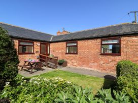 A brick house with a small garden and picnic bench at 2 Pines Farm Cottages in Ulleskelf
