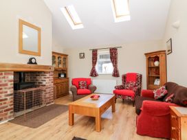 A living room with red and brown seating around a wooden coffee table and a brick fireplace at 2 Pines Farm Cottages in Ulleskelf