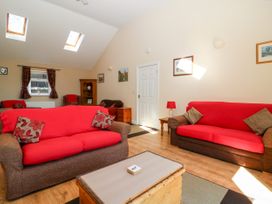 A living room with two red covered sofas a wooden chest coffee table and framed pictures at 2 Pines Farm Cottages in Ulleskelf