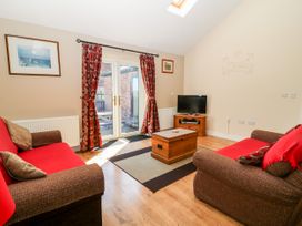 A living room with two sofas a wooden chest coffee table a television and glass doors at 2 Pines Farm Cottages Ulleskelf