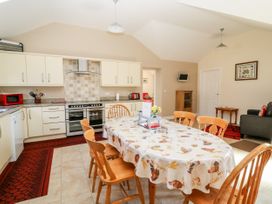 A kitchen and dining area with wooden chairs around a table covered with a patterned tablecloth at 2 Pines Farm Cottages in Ulleskelf