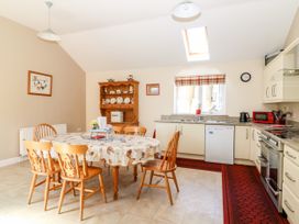 A kitchen with a dining table and wooden chairs near a wooden china cabinet and window at 2 Pines Farm Cottages in Ulleskelf