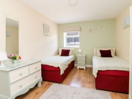 A bedroom with two single beds red base with white bedding and bedside table between at 2 Pines Farm Cottages Ulleskelf