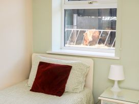 A bedroom with a bed pillow a bedside table and lamp and cows visible through the window at 2 Pines Farm Cottages in Ulleskelf