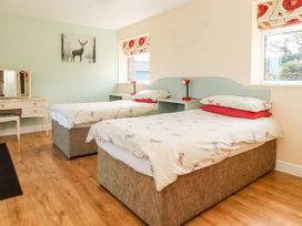 A bedroom with two single beds wooden floor and a dressing table at 2 Pines Farm Cottages Ulleskelf
