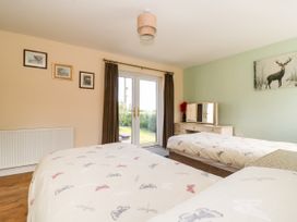 A bedroom with two single beds a dressing table with a mirror and glass doors leading outside at 2 Pines Farm Cottages Ulleskelf