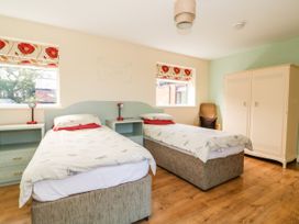 A bedroom with two single beds bedside tables lamps a wardrobe and a chair at 2 Pines Farm Cottages Ulleskelf