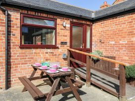 An outdoor patio area with a wooden picnic table set with plates and bowls outside a brick building at 2 Pines Farm Cottages in Ulleskelf
