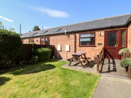 A garden area with a picnic table and a brick building with a ramp and door at 2 Pines Farm Cottages Ulleskelf