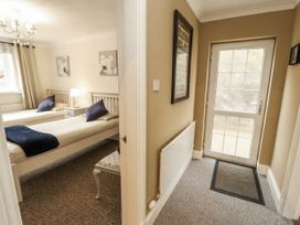 A bedroom with two beds and a door at White Gables in Great Clifton near Cockermouth