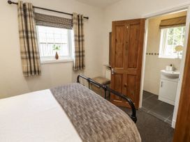 A bedroom with a bed and a door leading to a bathroom at White Gables in Great Clifton near Cockermouth