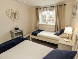 A bedroom with two beds and a window at White Gables in Great Clifton near Cockermouth