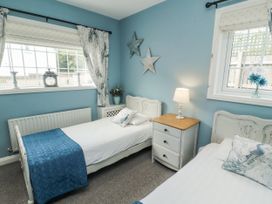 A bedroom with two single beds and a bedside table at White Gables in Great Clifton near Cockermouth