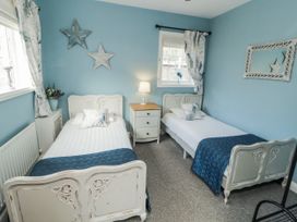 A bedroom with two single beds and a nightstand at White Gables in Great Clifton near Cockermouth