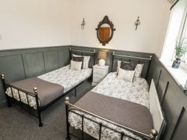A bedroom with two single beds and a nightstand at White Gables in Great Clifton near Cockermouth