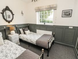 A bedroom with two beds and a window at White Gables in Great Clifton near Cockermouth