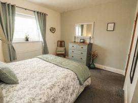 A bedroom with a bed and dresser at White Gables in Great Clifton near Cockermouth