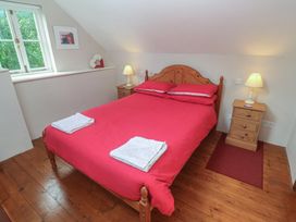 A bedroom with a red bed and lamps at Longhouse in St Keverne, Lizard Peninsula
