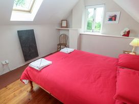 A bedroom with a bed and a chair at Longhouse in St Keverne, Lizard Peninsula