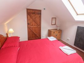 A bedroom with a red bed and wooden furniture at Longhouse St Keverne, Lizard Peninsula