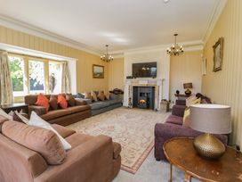 A living room with multiple sofas a fireplace and a television at Plas Gwynfryn in Llanbedr