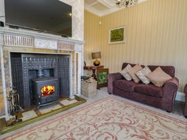 A living room with a fireplace TV purple sofa and patterned rug at Plas Gwynfryn in Llanbedr