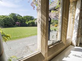 A window view of a garden with a lawn and trees at Plas Gwynfryn in Llanbedr