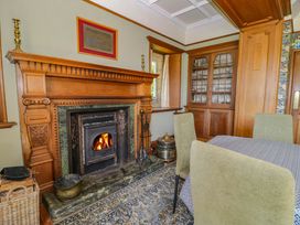 A dining room with a wooden fireplace and glass cabinet at Plas Gwynfryn in Llanbedr